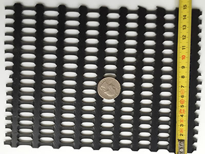 A coin is on the middle of the black biaxial geogrid sample, and there is a tape to measure its length, the number is 15 cm.