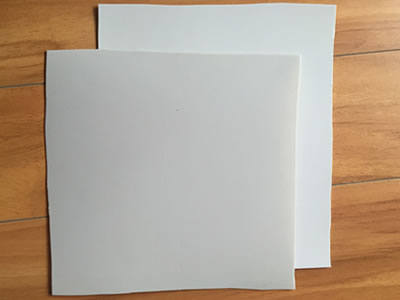 Two pieces of ECB geomembrane samples in two different colors are lying on the blue background.
