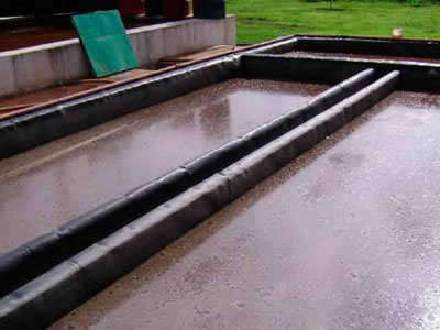 There are three water containments wrapped with black EVA geomembrane, and a grassland is beside it.