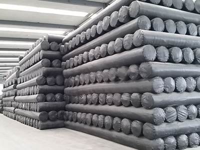 Many rolls of short fiber geotextile fabric are packaged with black plastic film, and pile up together in the factory.