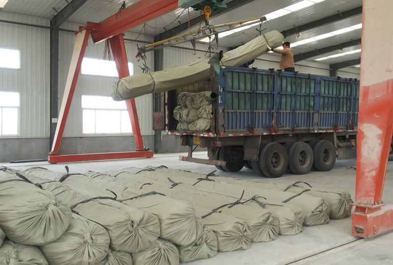 The worker is putting the packaged three dimensional composites drainage network rolls on the truck through the machine.