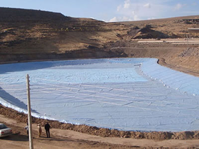 White ECB geomembrane is laid on a large area, and there are three people, two cars beside it.