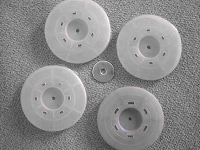 Four white porous hot melt gaskets are put on the orange background, and a small piece of iron plate is in the middle.